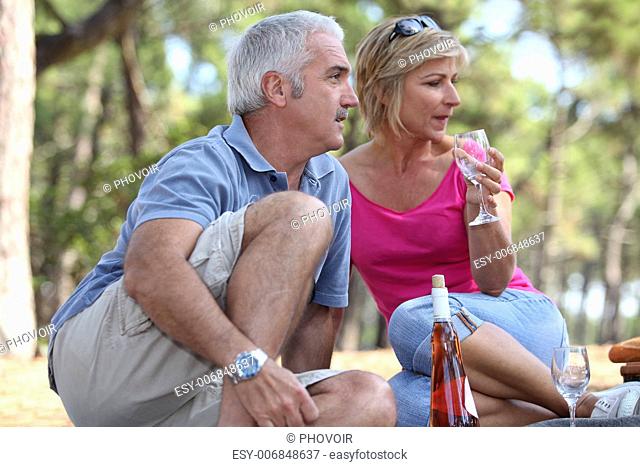 a mid age couple having a picnic in a pine forest