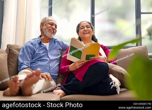 A HAPPY OLD COUPLE ENJOYING READING A BOOK