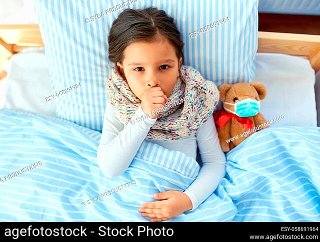 sick coughing girl with teddy bear lying in bed