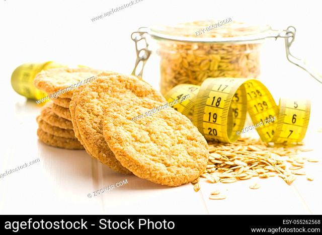 Crispy oatmeal cookies and measuring tape on white table