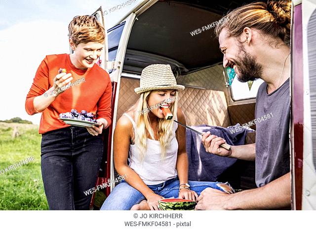 Happy friends eating a watermelon in a van