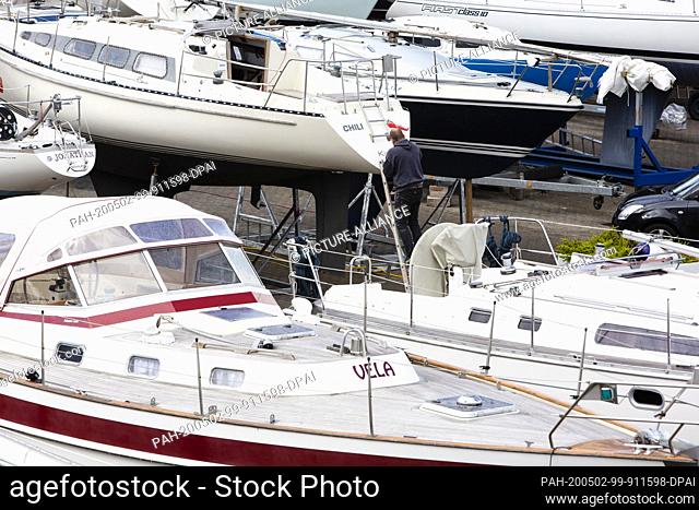 01 May 2020, Schleswig-Holstein, Kiel: A man carries out repair work on his boat in the Olympic harbour in Kiel-Schilksee