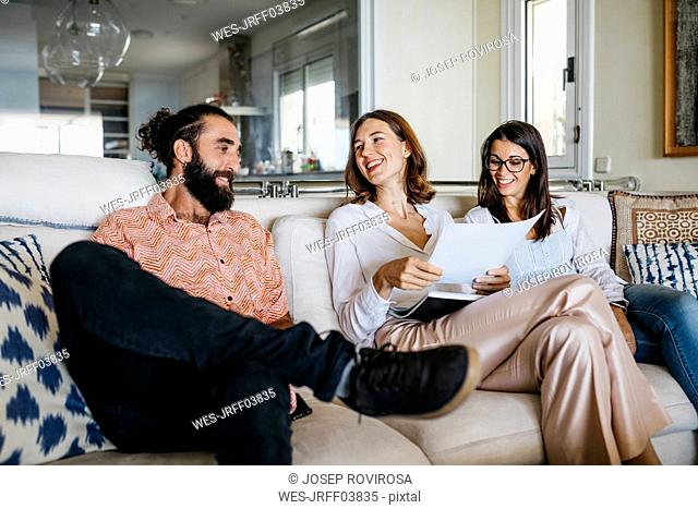 Coworkers and friends sitting on couch with papers