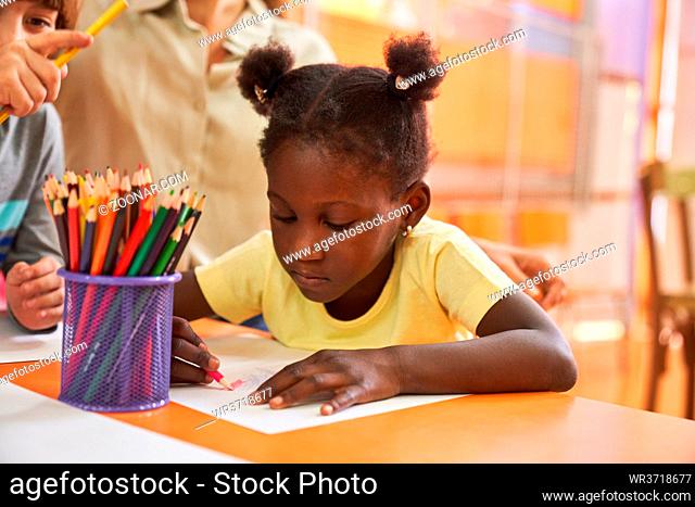 Kreatives afrikanisches Mädchen mit Zöpfen malt Bild mit Buntstiften im Malkurs im Kindergarten