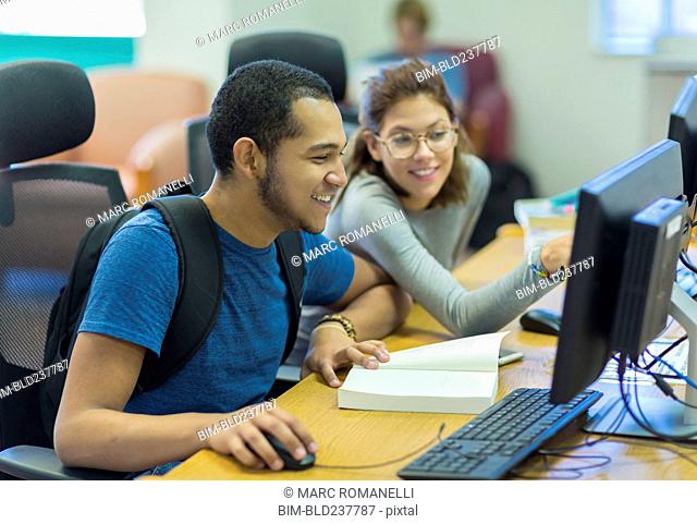 Mixed Race boy and girl using computer in library