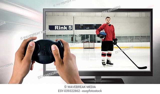 Hands holding gaming controller with hockey player on television