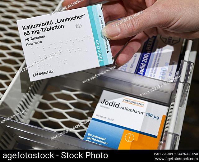 08 March 2022, Saxony, Leipzig: A pharmacist takes a pack of high-dose iodine tablets from a supply cabinet, next to which are weaker doses for thyroid...