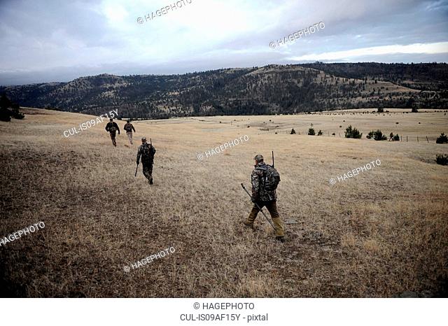 Four deer hunters walking across field, John Day, Oregon, USA