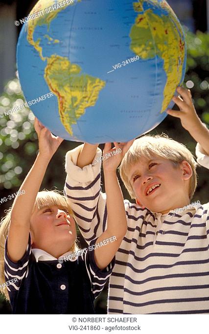 outdoor, half-figure, blue-white dressed blond girl and boy, 4-6 years old, study the globe printed on a waterball  - GERMANY, 21/08/2004