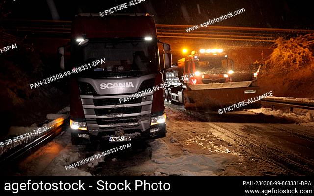 07 March 2023, Hesse, Hessisch Lichtenau: A gritting vehicle drives next to a broken-down truck. The onset of winter shortly after the meteorological start of...