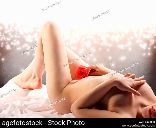 Attractive nude woman lying on white bed sheets over gray background