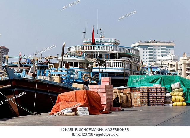 Cargo in front of an old wooden cargo ship, dhow or dau on Dubai Creek, Dubai, United Arab Emirates, Middle East, Asia