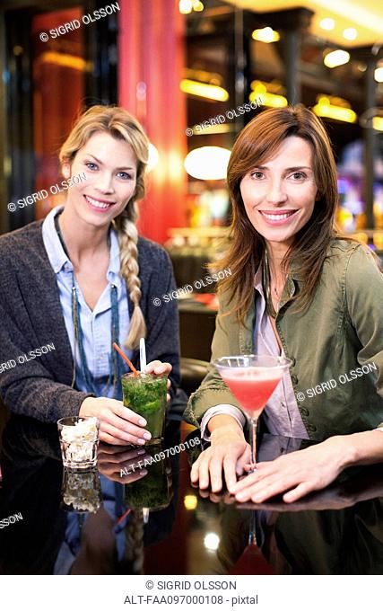 Women enjoying cocktail at bar, portrait