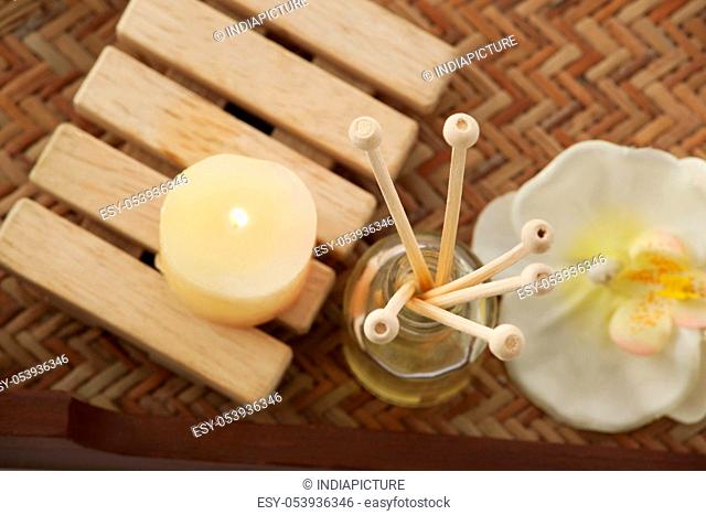 Close-up of reed diffuser with candle and orchid