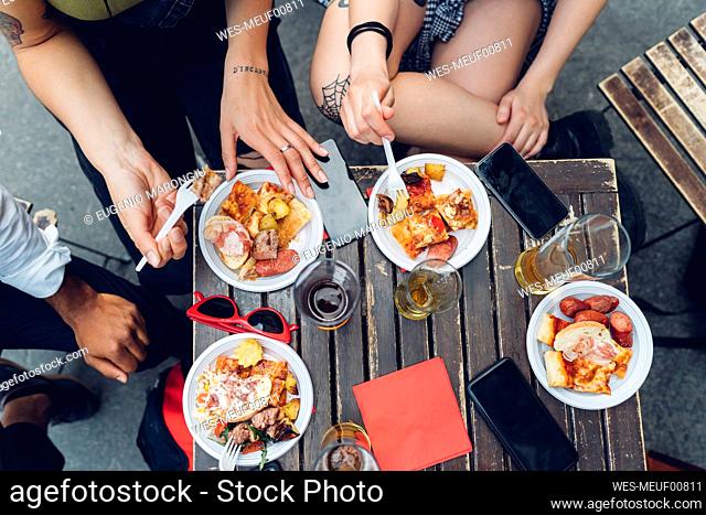 Friends sitting at table outdoors eating snacks