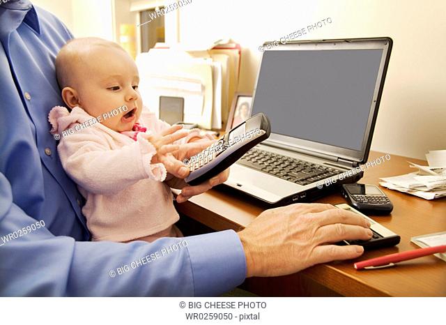 Businessman working with baby on lap