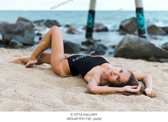 Beautiful young woman wearing swimsuit lying on the beach