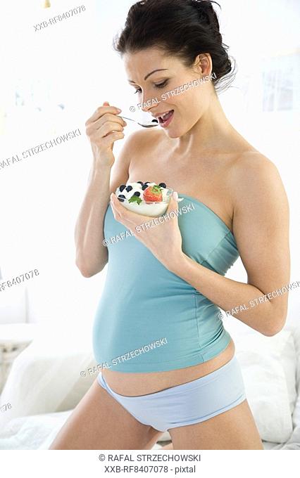 pregnant woman eating joghurt with fruits