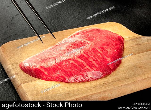 Kobe meat, wagyu beef steak, raw, with a carving fork on a black background with a place for text