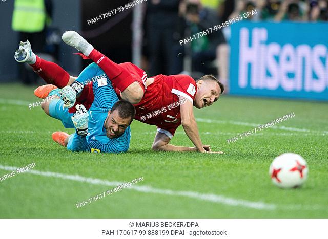 Russia's Aleksandr Burharov falls over New Zealand goalie Stefan Marinovic during the Confederations Cup Group A soccer match between Russia and New Zealand at...
