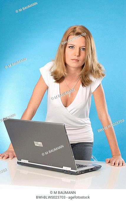 young woman at desk with laptop standing up