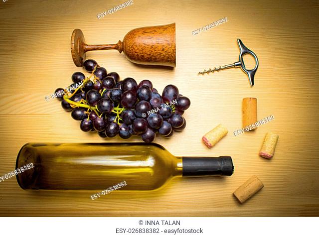 The empty bottle of wine with corkscrews and glass of coconut on wooden background