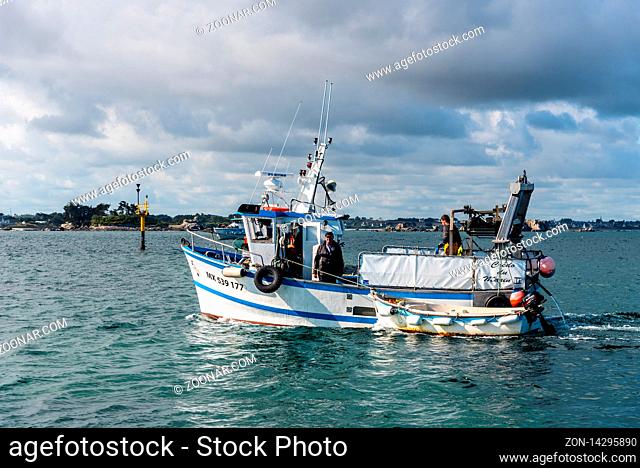 Roscoff, France - July 31, 2018: Small fishing boat in the bay of Roscoff against the waterfront of the town