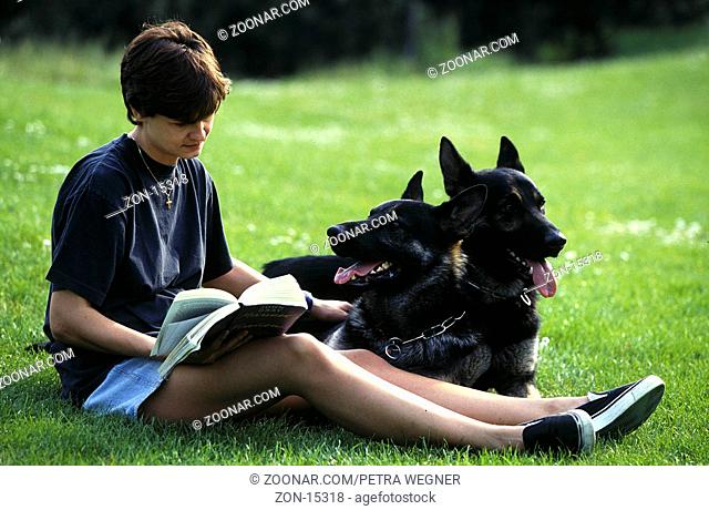 Junge Frau mit Deutschen Schaeferhunden liest Buch auf Wiese  /  Young Woman with German Shepherds reading book  /  [Tiere, animals, Saeugetiere, mammals