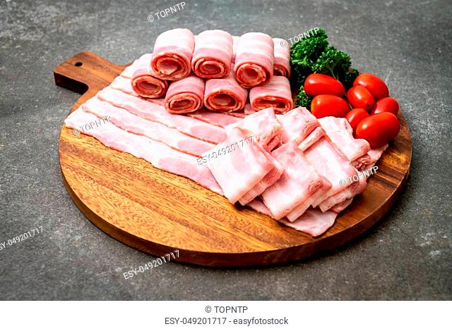 sliced raw pork bacon on wood board
