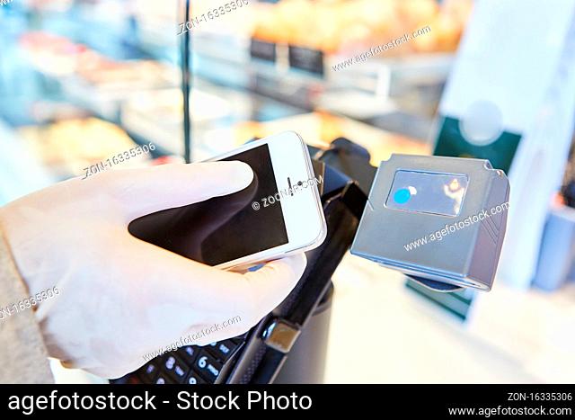 Hand in Einweghandschuhen mit Smartphone für Mobile Payment an der Kasse