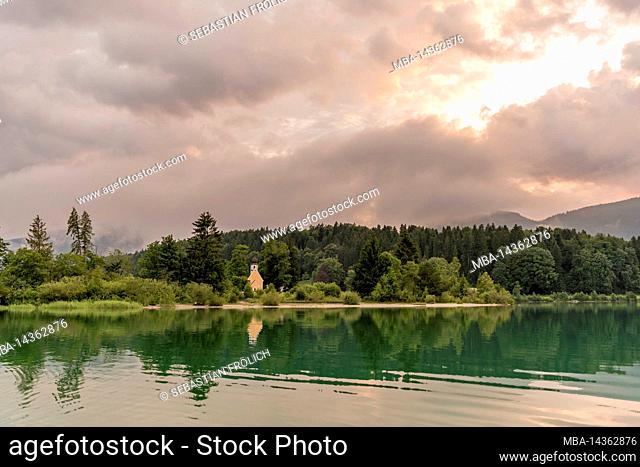 The chapel of St. Margareth on the small peninsula of Zwergern in Lake Walchen, photographed from a boat. In the background the Simetsberg in dense clouds just...