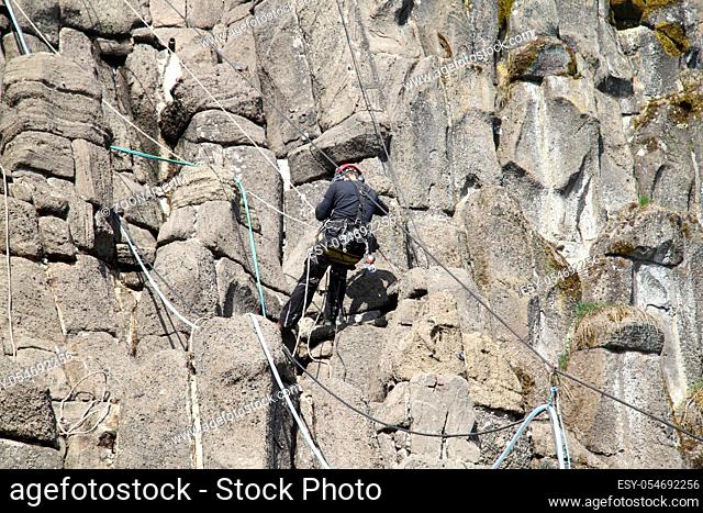 A rope access works in a rock wall	 Ein Industriekletterer arbeitet in einer Felswand