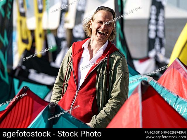 12 August 2021, Schleswig-Holstein, Sankt Peter-Ording: Actor Ralf Bauer stands on the beach of Sankt Peter-Ording between sails of kites