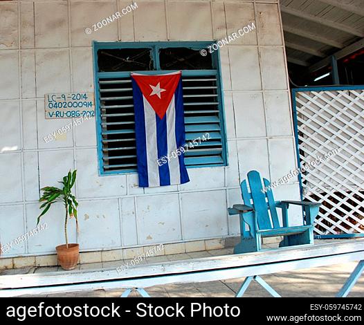 Cuban flag attached to a window and an old wooden chair