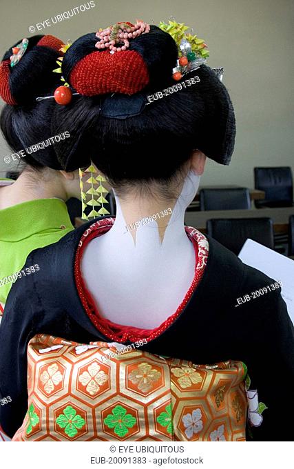 Gion District. Back of Geisha attending a class at Mia Garatso school for Geisha wearing black silk kimono with gold and green obi