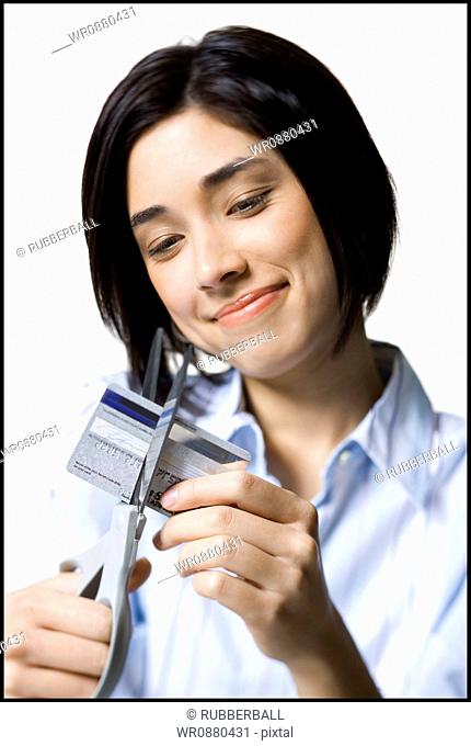 Close-up of a young woman cutting a credit card with a pair of scissors