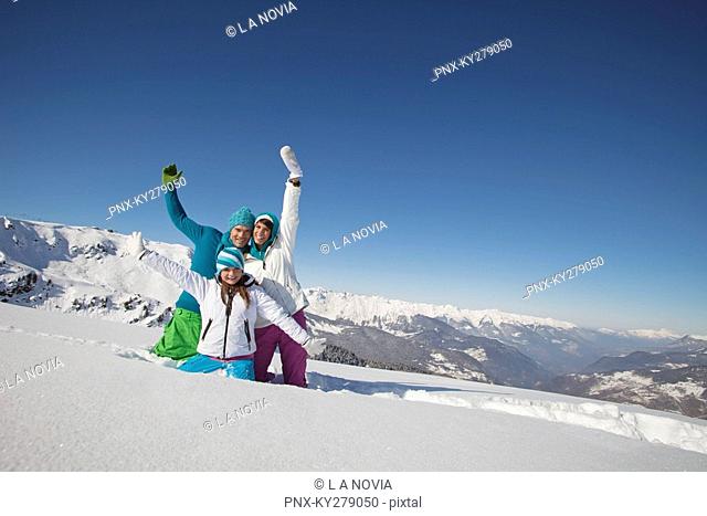 Couple and daughter in ski wear, playing in snow