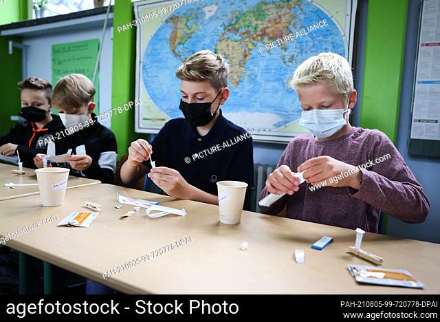 05 August 2021, Hamburg: Arjen (r-l), York and other pupils of class 6a at the Goethe-Gymnasium in Hamburg-Lurup, take a Corona quick test in the classroom on...
