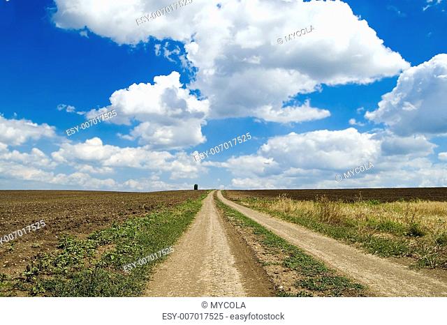 a dirt road is directed in clouds
