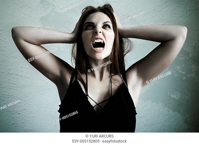 Young beautiful female vampire howling with blood-thirsty rage