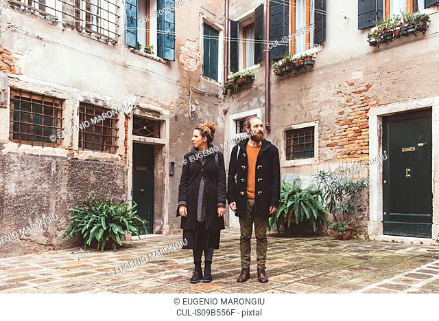 Couple in courtyard looking in opposite directions, Venice, Italy