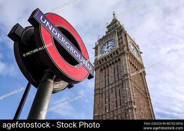 30 October 2022, Great Britain, London: A sign with the logo of the London Underground stands in front of the Elizabeth Tower, where the bell Big Ben hangs