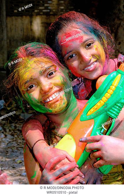 Coloured faces of young girls holding syringe pichkari enjoying holi festival MR 364