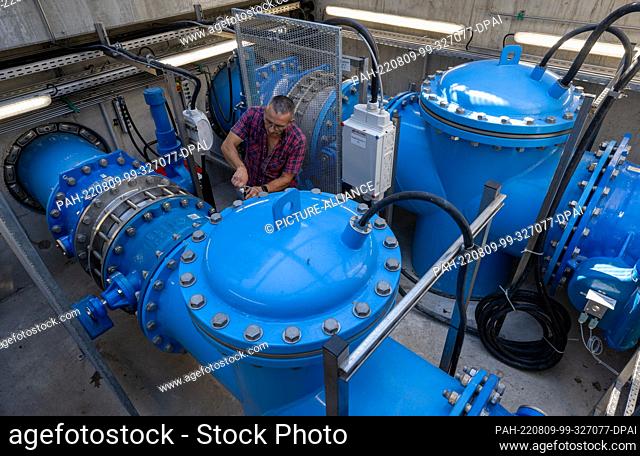 09 August 2022, Saxony, Grimma: An employee of the Grimma river maintenance department stands between pumps in the pumping station on the Mulde River in Grimma