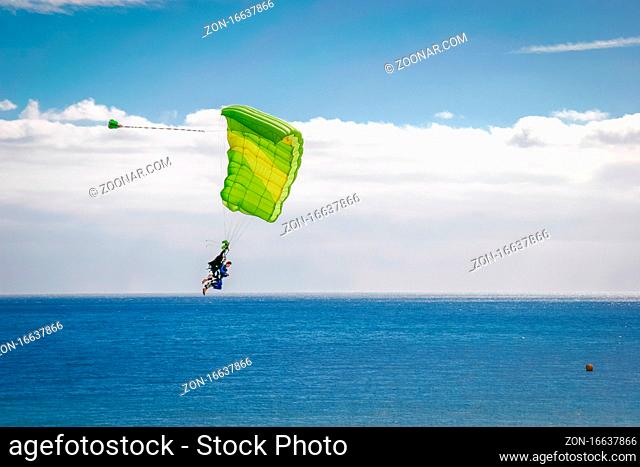 Couple paragliding over atlantic ocean towards Playa del Ingles beach Gran Canaria