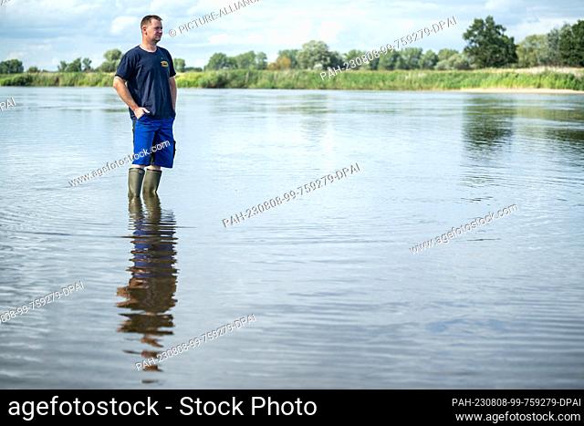 PRODUCTION - 05 August 2023, Brandenburg, Kuhbrücke: Fisherman Andre Schneider stands in the Oder River. The Schneider family runs a fishing farm with a camping...