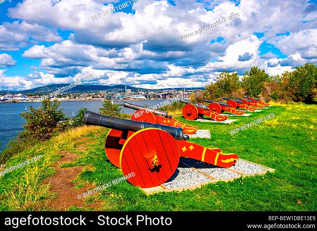 Oslo, Ostlandet / Norway - 2019/09/02: Historic XIX century Napoleonic war cannons battery on Hovedoya island of Oslofjord harbor with metropolitan Oslo in...