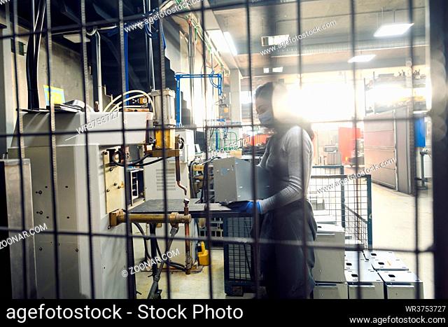 woman working in the metal industry in the production of new machines wears a face mask during work due to the coronavirus pandemic