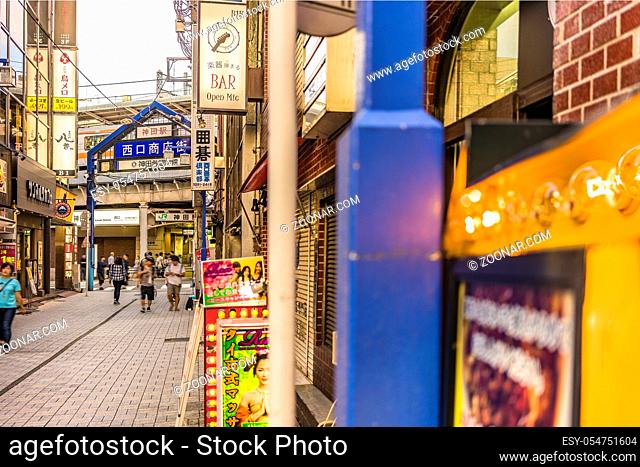 Blue metal entrance gate and neon signs in the shopping street from the west exit of Kanda Station on the Yamanote Line. The street extends over 300 meters and...