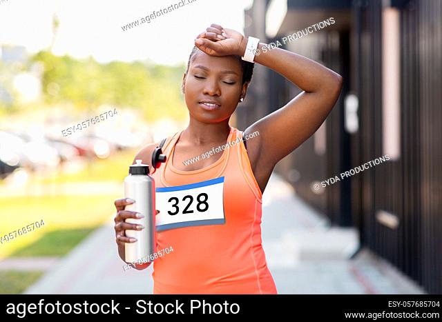 tired female marathon runner with bottle of water